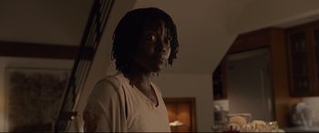 Movie still from “Us” (2019), directed by Jordan Peele – A person with long black hair is standing in a living room; Close Up shot, Over the shoulder angle