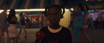 Movie still from “Us” (2019), directed by Jordan Peele – A young girl holding an apple on top of a stick; Close Up shot, Over the shoulder angle