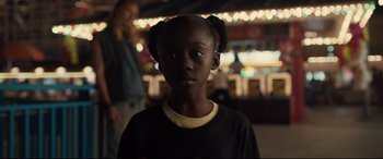 Movie still from “Us” (2019), directed by Jordan Peele – A young girl is standing in front of a carousel; Close Up shot, High angle