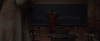 Movie still from “Us” (2019), directed by Jordan Peele – A person standing in front of a chalkboard in a room; Wide shot, Over the shoulder angle