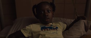 Movie still from “Us” (2019), directed by Jordan Peele – A little girl sitting in a chair with her eyes wide open; Close Up shot, High angle