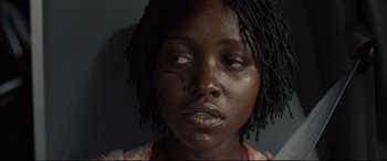 Movie still from “Us” (2019), directed by Jordan Peele – A person with black hair; Close Up shot, High angle