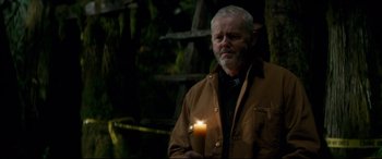 Movie still from “Horns” (2013), directed by Alexandre Aja – An older man holding a lit candle in the dark; Medium shot, Over the shoulder angle