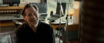 Movie still from “Horns” (2013), directed by Alexandre Aja – A man sitting in front of a microphone in a room; Close Up shot, Over the shoulder angle