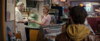 Movie still from “Horns” (2013), directed by Alexandre Aja – A woman in a pink shirt is working in a kitchen; Medium shot, Over the shoulder angle