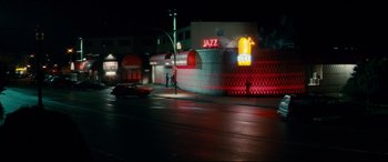 Movie still from “Horns” (2013), directed by Alexandre Aja – A car driving down a street near a building; Extreme Wide shot, High angle