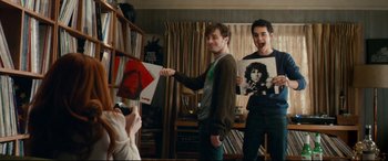 Movie still from “Horns” (2013), directed by Alexandre Aja – Two young men holding up records in front of a camera; Medium shot, Over the shoulder angle