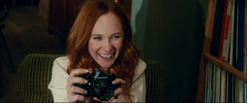 Movie still from “Horns” (2013), directed by Alexandre Aja – A woman smiling while holding a camera in her hands; Close Up shot, Over the shoulder angle