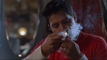Movie still from “Hostel” (2005), directed by Eli Roth – A man in a red shirt is smoking a cigarette; Close Up shot, Low angle