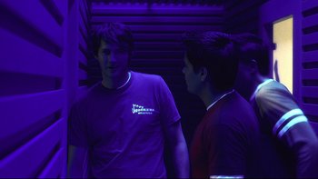 Movie still from “Hostel” (2005), directed by Eli Roth – Two young men standing next to each other in a purple room; Medium shot, Over the shoulder angle