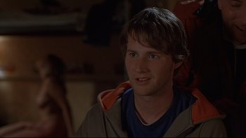 Movie still from “Hostel” (2005), directed by Eli Roth – A young man is smiling for the camera; Close Up shot, Over the shoulder angle