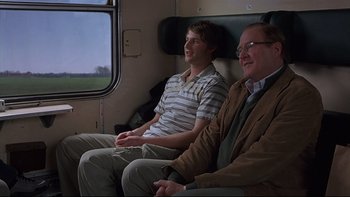 Movie still from “Hostel” (2005), directed by Eli Roth – Two men sitting on a train looking out the window; Medium shot, Over the shoulder angle