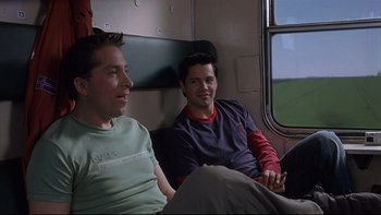 Movie still from “Hostel” (2005), directed by Eli Roth – Two men sitting on a train looking out the window; Medium shot, Over the shoulder angle