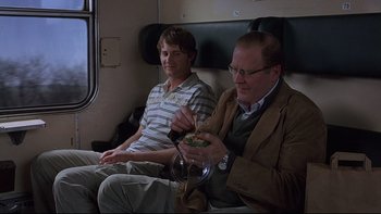 Movie still from “Hostel” (2005), directed by Eli Roth – Two men are sitting on a train and eating food; Medium shot, Over the shoulder angle