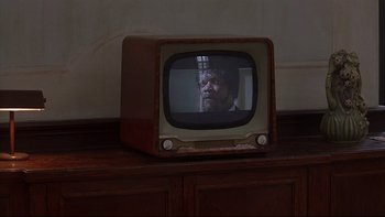Movie still from “Hostel” (2005), directed by Eli Roth – An old tv with a man on the screen; Extreme Close Up shot, Over the shoulder angle