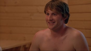 Movie still from “Hostel” (2005), directed by Eli Roth – A young man sitting in a sauna smiling for the camera; Close Up shot, Over the shoulder angle