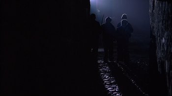 Movie still from “Hostel” (2005), directed by Eli Roth – A group of people standing in the dark; Wide shot, Low angle