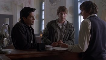 Movie still from “Hostel” (2005), directed by Eli Roth – A group of men sitting around a table; Medium shot, Over the shoulder angle