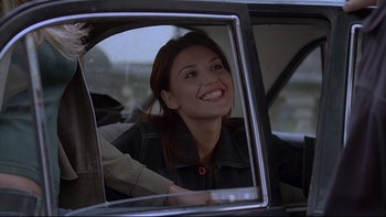 Movie still from “Hostel” (2005), directed by Eli Roth – A woman sitting in the back seat of a car smiling; Close Up shot, Over the shoulder angle