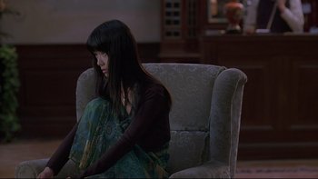 Movie still from “Hostel” (2005), directed by Eli Roth – A woman sitting in a chair with her arm resting on her knee; Medium shot, High angle