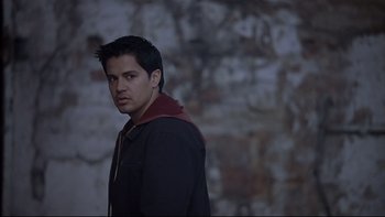 Movie still from “Hostel” (2005), directed by Eli Roth – A young man standing in front of a brick wall; Medium shot, Over the shoulder angle