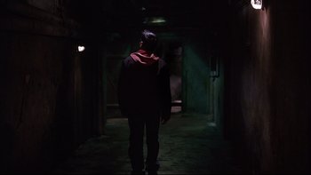 Movie still from “Hostel” (2005), directed by Eli Roth – A man is standing in the dark in a dark room; Wide shot, High angle