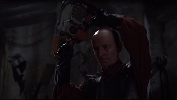 Movie still from “Hostel” (2005), directed by Eli Roth – A man holding an electric saw in his hand; Close Up shot, Low angle