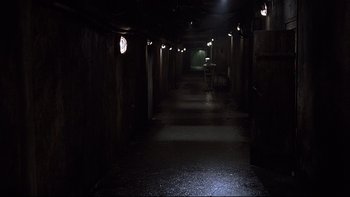 Movie still from “Hostel” (2005), directed by Eli Roth – A long dark hallway with lights on the ceiling; Extreme Wide shot, High angle