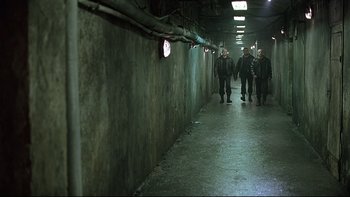 Movie still from “Hostel” (2005), directed by Eli Roth – A group of people walking down a dark hallway; Wide shot, High angle
