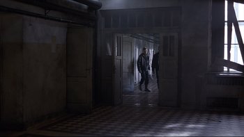 Movie still from “Hostel” (2005), directed by Eli Roth – A group of people walking through a dark hallway; Wide shot, High angle