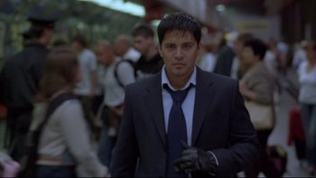 Movie still from “Hostel” (2005), directed by Eli Roth – A man in a suit and tie standing next to a crowd of onlookers; Medium shot, Low angle