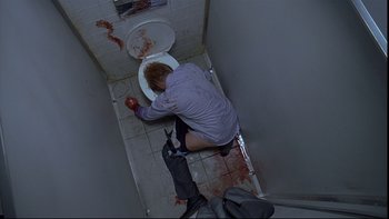 Movie still from “Hostel” (2005), directed by Eli Roth – A man is sitting on the floor of a bathroom; Wide shot, Overhead angle