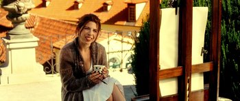 Movie still from “Hostel: Part II” (2007), directed by Eli Roth – A beautiful young lady sitting on a bench holding a camera; Medium shot, Low angle