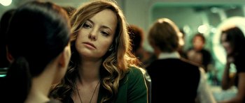 Movie still from “Hostel: Part II” (2007), directed by Eli Roth – A woman sitting in front of a group of other people; Close Up shot, Over the shoulder angle