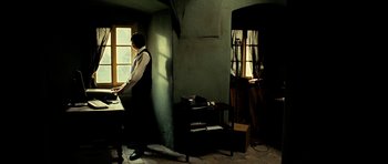 Movie still from “Hostel: Part II” (2007), directed by Eli Roth – A man standing at a table in a room; Wide shot, High angle