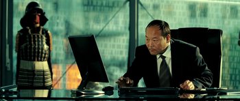 Movie still from “Hostel: Part II” (2007), directed by Eli Roth – A man in a suit and tie looking at a computer screen; Medium shot, Low angle