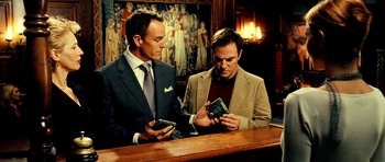 Movie still from “Hostel: Part II” (2007), directed by Eli Roth – Two men looking at their cell phones at a bar; Medium shot, Low angle