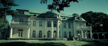 Movie still from “Hostel: Part II” (2007), directed by Eli Roth – A large white building sitting on top of a green hill; Extreme Wide shot, Low angle