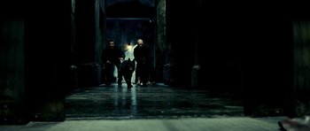 Movie still from “Hostel: Part II” (2007), directed by Eli Roth – Two men and a dog sitting in a dark room; Wide shot, Low angle