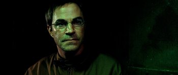 Movie still from “Hostel: Part II” (2007), directed by Eli Roth – A person wearing glasses and a green jacket; Close Up shot, Low angle