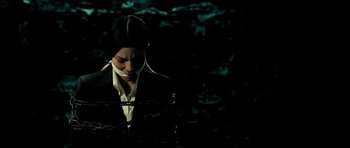 Movie still from “Hostel: Part II” (2007), directed by Eli Roth – A woman in a black suit is tied to a barbed wire fence; Medium shot, Low angle