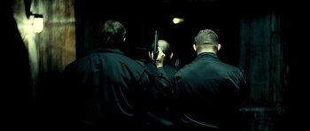 Movie still from “Hostel: Part II” (2007), directed by Eli Roth – A group of men standing next to each other holding guns; Medium shot, Over the shoulder angle