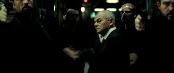 Movie still from “Hostel: Part II” (2007), directed by Eli Roth – A man in a suit and tie standing next to two other men; Medium shot, Low angle