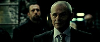 Movie still from “Hostel: Part II” (2007), directed by Eli Roth – A person wearing a suit and tie; Close Up shot, Over the shoulder angle