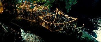 Movie still from “Hostel: Part II” (2007), directed by Eli Roth – A group of people sitting on a bench at night; Extreme Wide shot, High angle