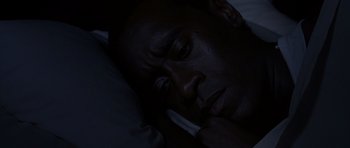 Movie still from “Hotel Rwanda” (2004), directed by Terry George – A man laying in bed with his eyes closed; Close Up shot, High angle