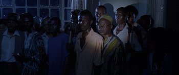 Movie still from “Hotel Rwanda” (2004), directed by Terry George – A group of people standing in a room; Medium shot, High angle