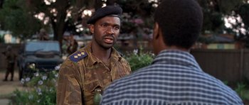 Movie still from “Hotel Rwanda” (2004), directed by Terry George – A man in a uniform talking to another man; Close Up shot, Over the shoulder angle