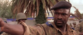 Movie still from “Hotel Rwanda” (2004), directed by Terry George – A man in a military uniform is standing next to a tree; Close Up shot, Low angle