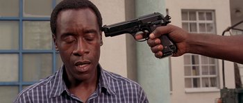 Movie still from “Hotel Rwanda” (2004), directed by Terry George – A man holding a gun up to his face; Close Up shot, Over the shoulder angle